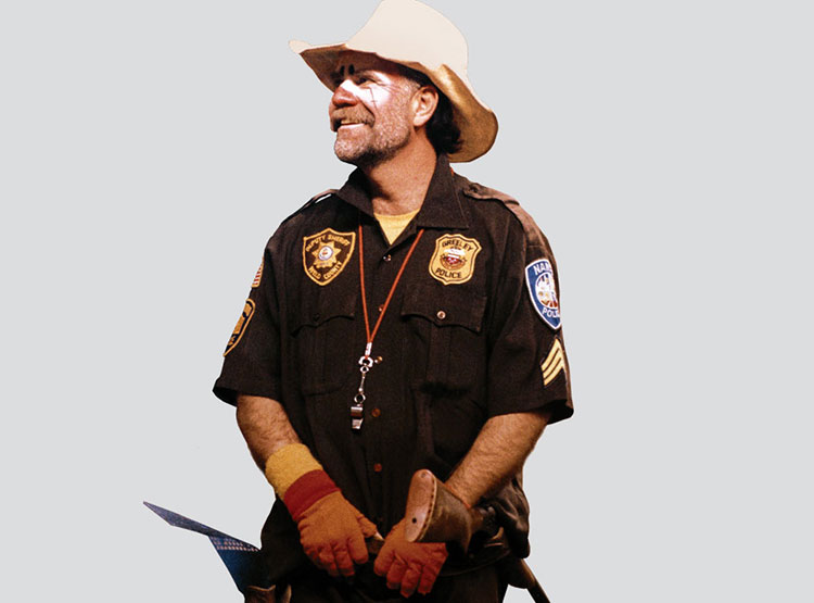 Tom Feller dressed as a rodeo clown, smiling and looking away.